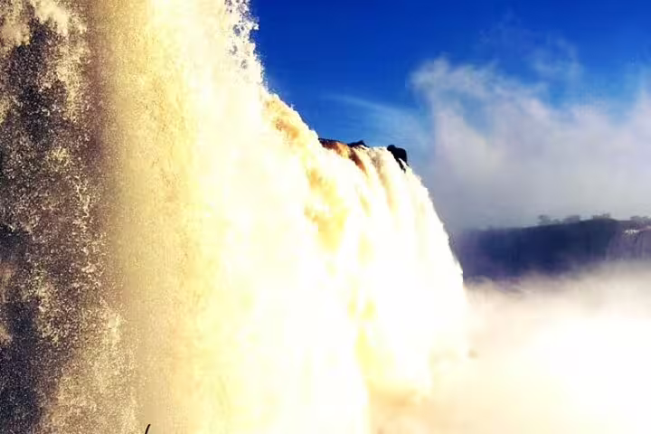 Breathtaking view of Iguazu Falls cascading under a clear blue sky, highlighting the power and beauty of the natural wonder.