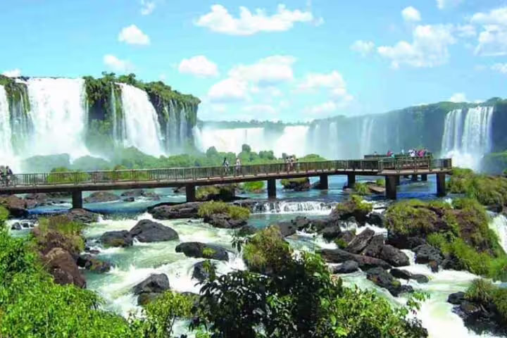 Tourists admire the breathtaking Iguazu Falls from a scenic walkway, showcasing the natural beauty of Argentina and Brazil.