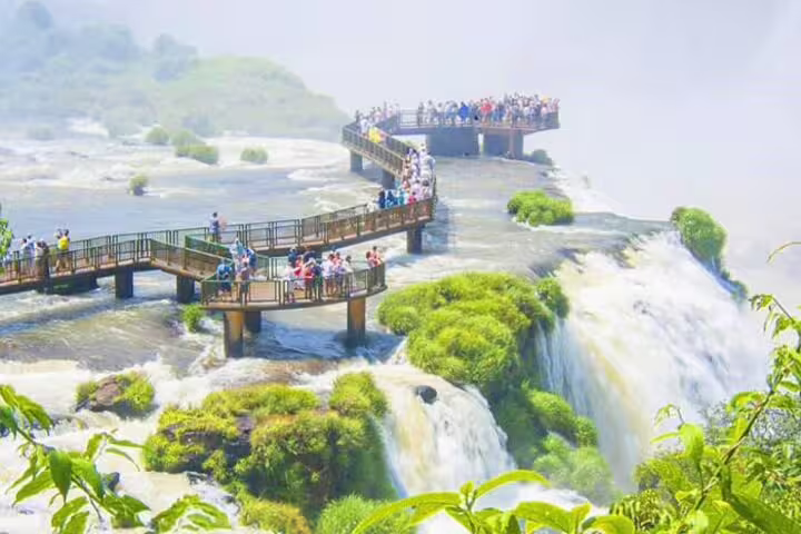 Visitors explore walkways over the cascading waters of Iguazu Falls, experiencing the lush scenery and powerful flow.