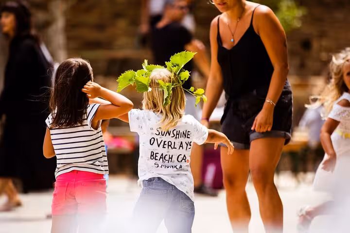 Children playing outdoors on Ikaria, wearing a vine wreath during a traditional village gathering on a Greek island tour
