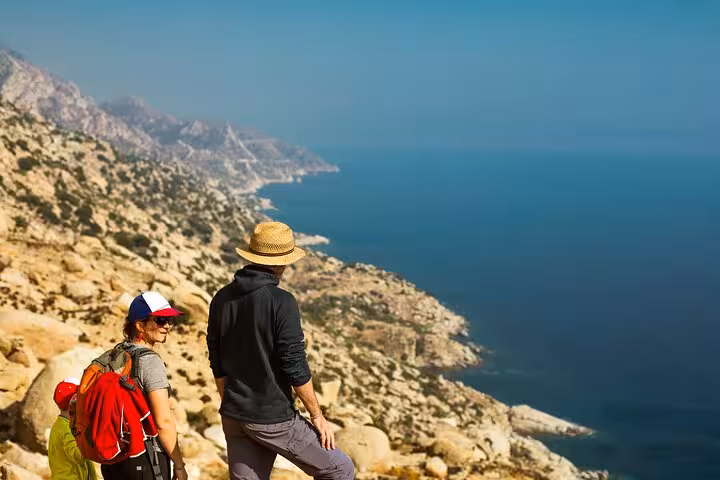 Family hikers overlooking dramatic cliffs and deep blue Aegean Sea on Ikaria’s west side, included in the island’s highlights tour
