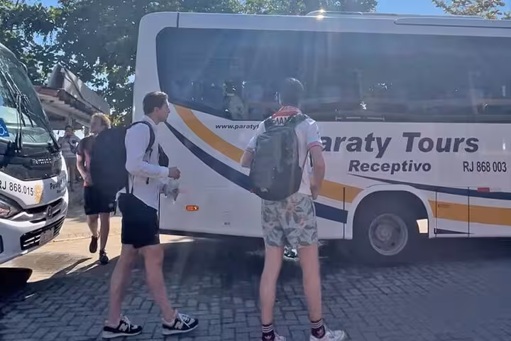 Travelers boarding a Paraty Tours bus for a shared shuttle transfer from Ilha Grande.