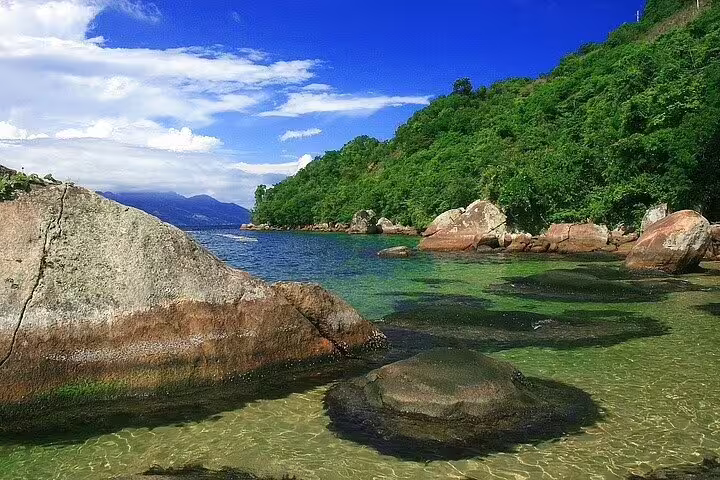 Scenic coastal view of Ilha Grande's clear waters and rocky shoreline, perfect for private boat excursions and relaxation.