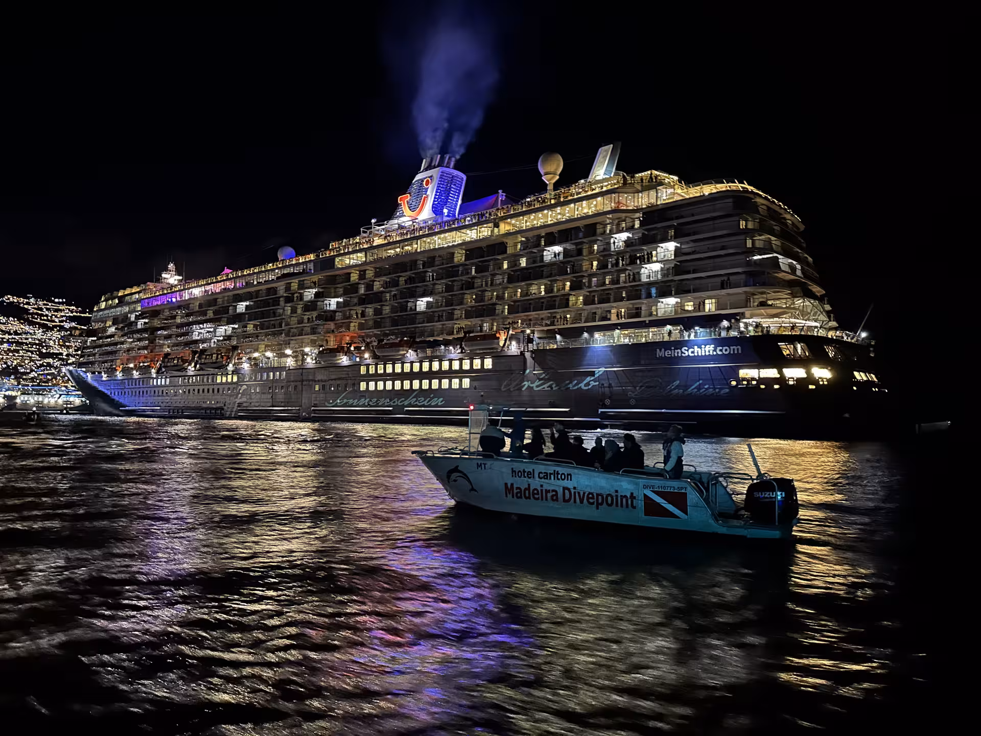 Illuminated cruise ship and smaller boat on the water, celebrating New Year's Eve at June's Atlantic Festival.