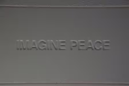 Embossed 'Imagine Peace' text on a grey surface at the Imagine Peace Tower on Videy Island