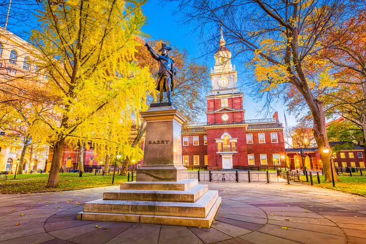 Barry statue and Independence Hall red brick building with autumn trees in Philadelphia