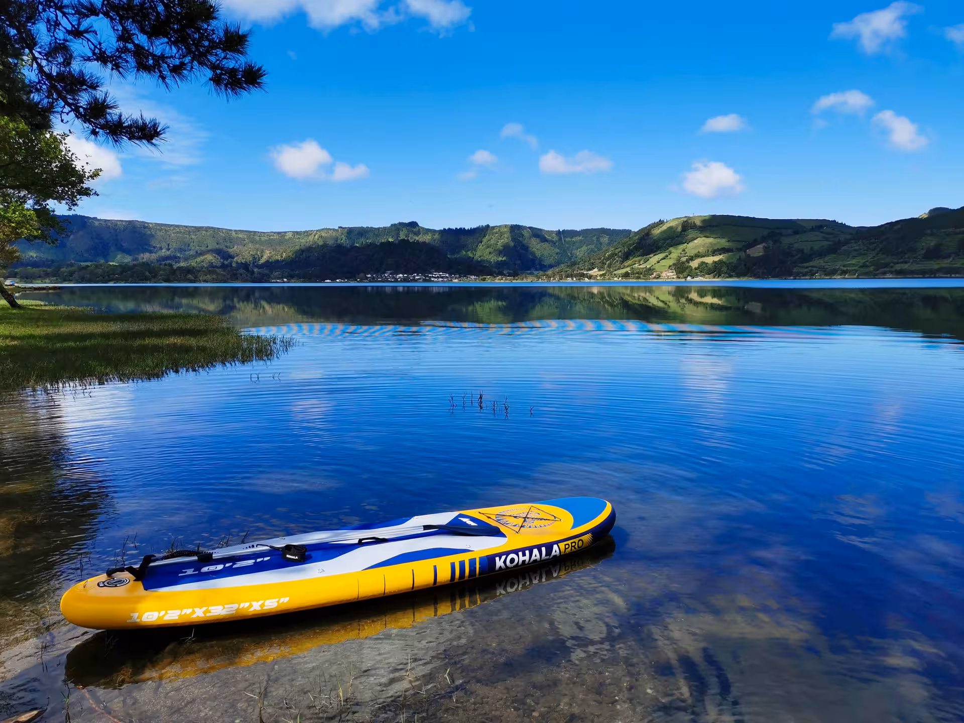 Inflatable paddleboard on calm Sete Cidades lake with green crater hills, highlighting Azores Seven Cities Experience