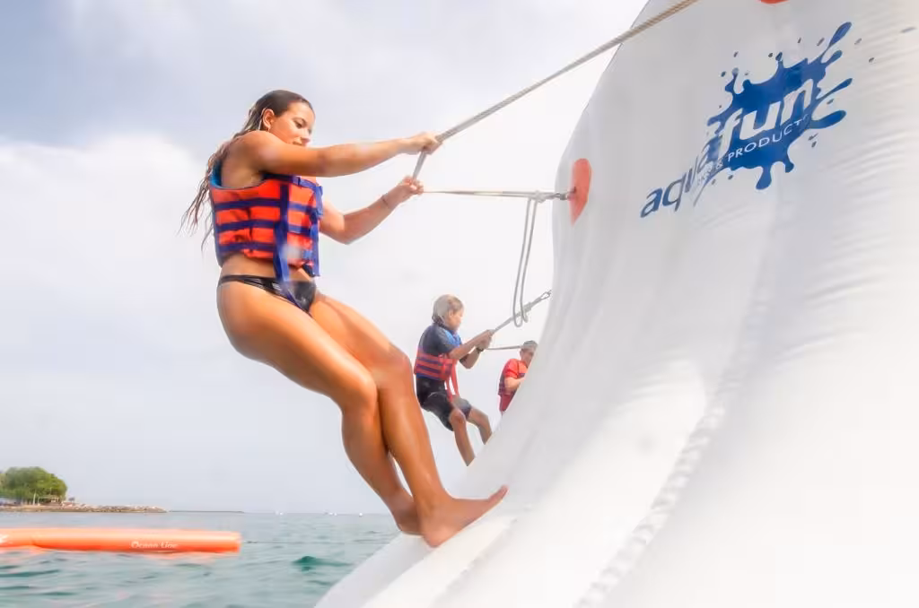 Woman and kids climbing a giant inflatable wall at a fun ocean inflatable waterpark adventure activity