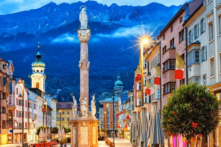Innsbruck Old Town at dusk with Maria Theresa Street column and Alps on private day tour from Munich
