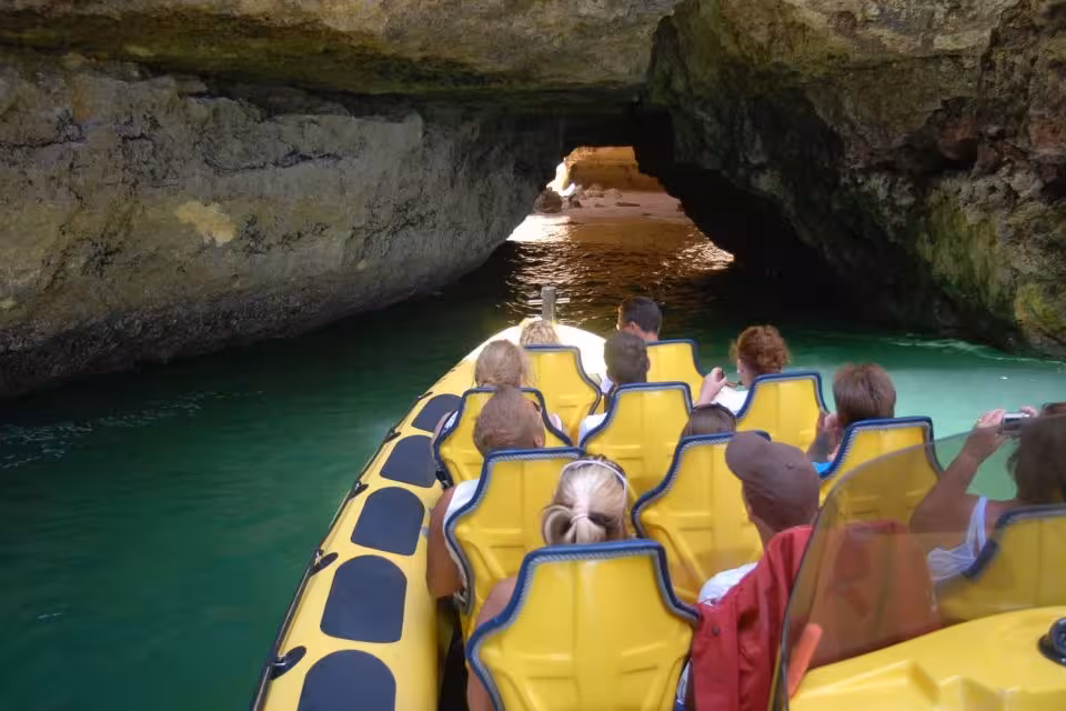 Visitors on an Insonia boat navigate through the narrow passage of a picturesque sea cave in Algarve.