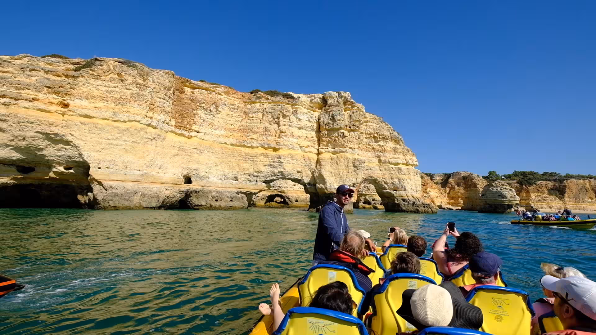 Visitors enjoy a scenic boat ride past Algarve's dramatic cliffs on the Insonia Private tour under clear blue skies.
