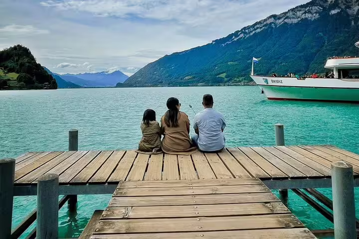 Family sitting on a wooden dock overlooking turquoise waters and mountains on the Interlaken private tour route.