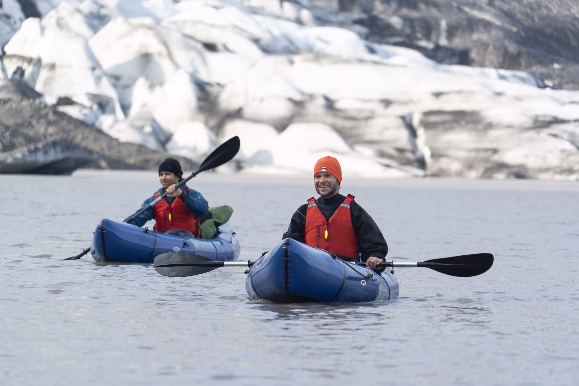 Two packrafters paddle a glacial lake in inflatable boats during an Intro to Glacier Packrafting adventure