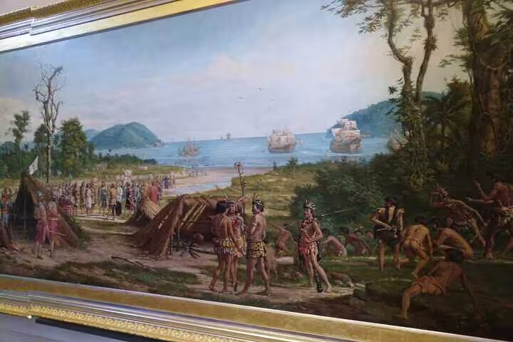 Historic painting depicting indigenous life and European ships, showcasing Brazil's colonial era at the Ipiranga Museum.