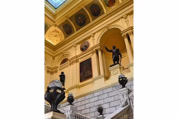 Interior of Ipiranga Museum featuring grand staircase with statues and historical portraits, highlighting Brazil's rich heritage.