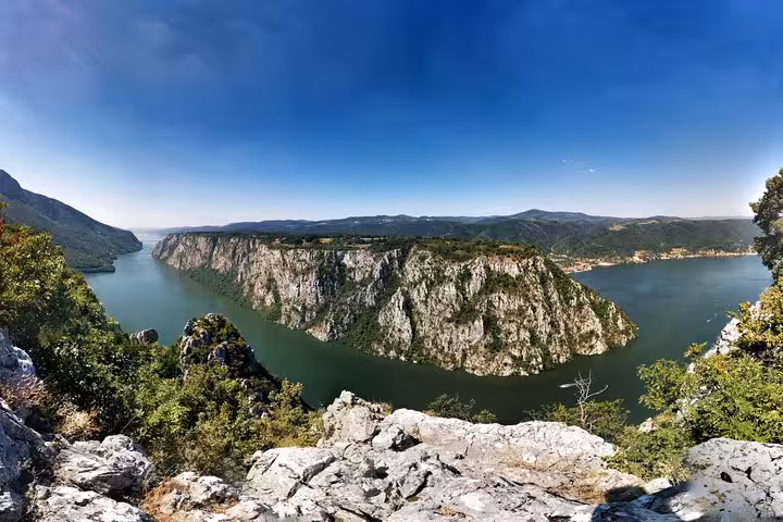 Panoramic view of the Iron Gate Gorge along the Danube River, showcasing dramatic cliffs and lush greenery.