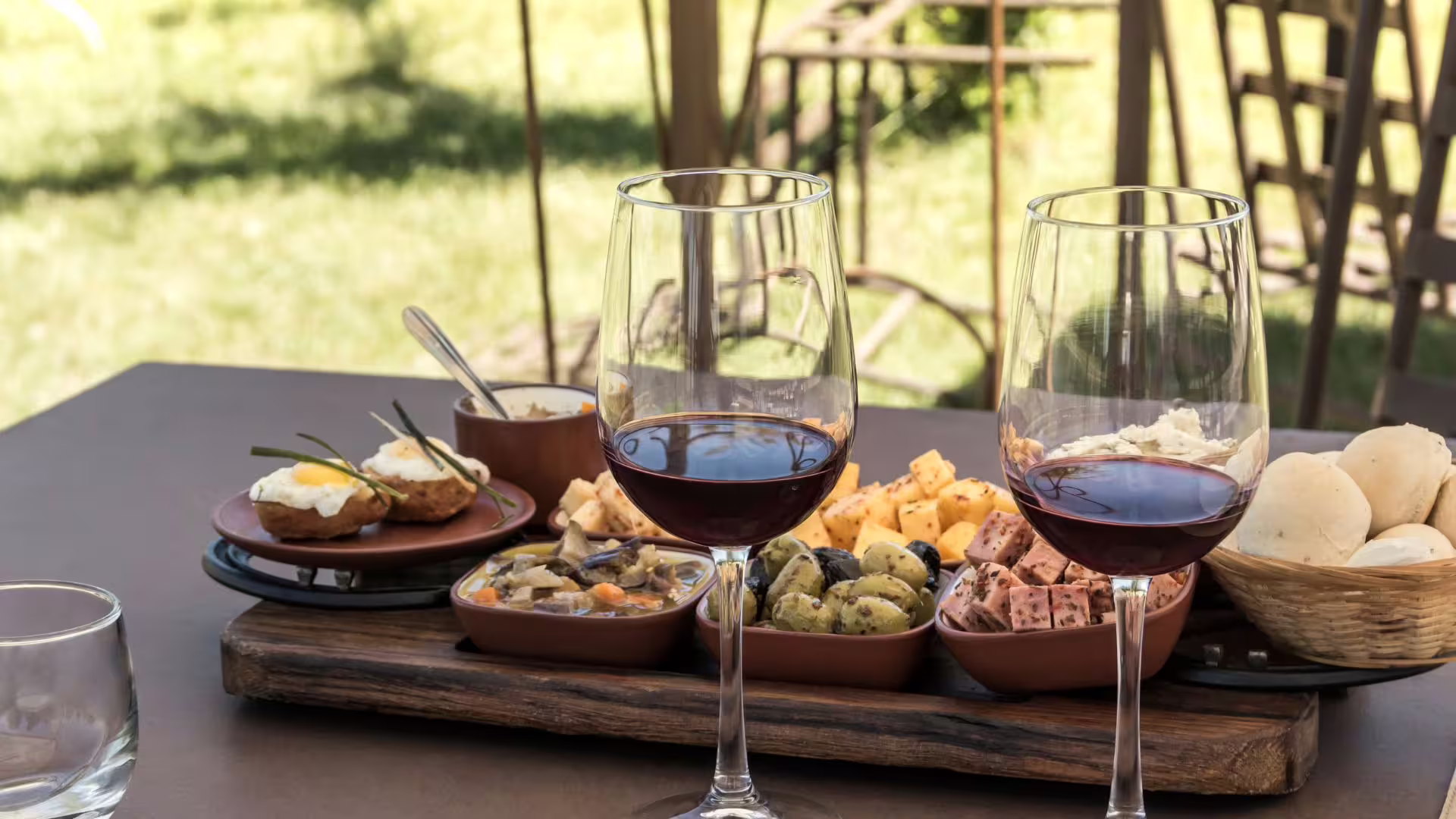 Irpinia wine tasting table with red wine glasses, local cheeses, olives and breads set outdoors on a sunny countryside terrace
