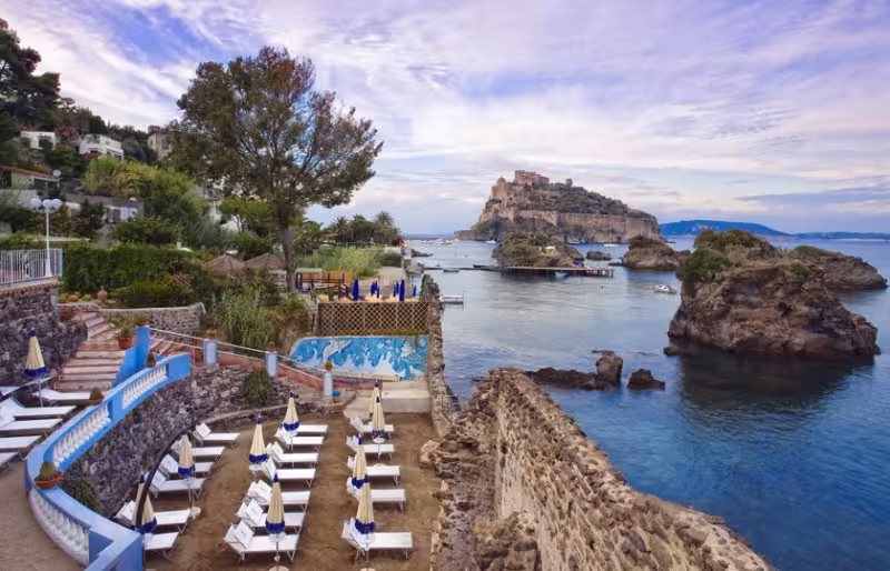 Ischia boat tour view of Castello Aragonese and rocky bay, ideal for scenic cruise and swimming stops