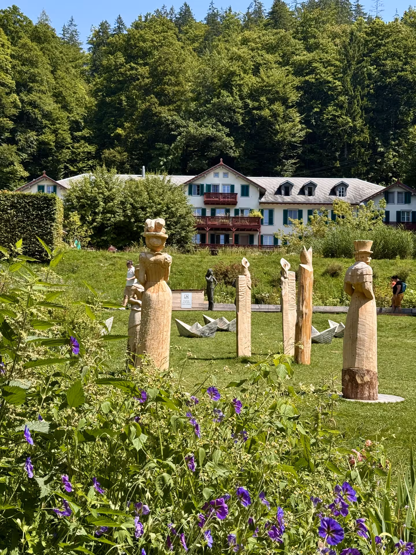 Wooden sculptures and wildflowers at Grandhotel Giessbach gardens on Iseltwald & Giessbach e-bike tour