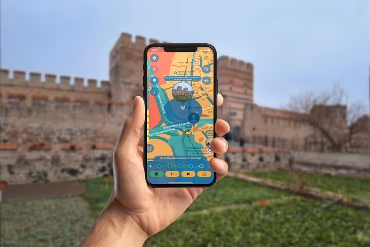 Hand holding smartphone with self-guided tour app map near Istanbul's ancient Constantinople city walls