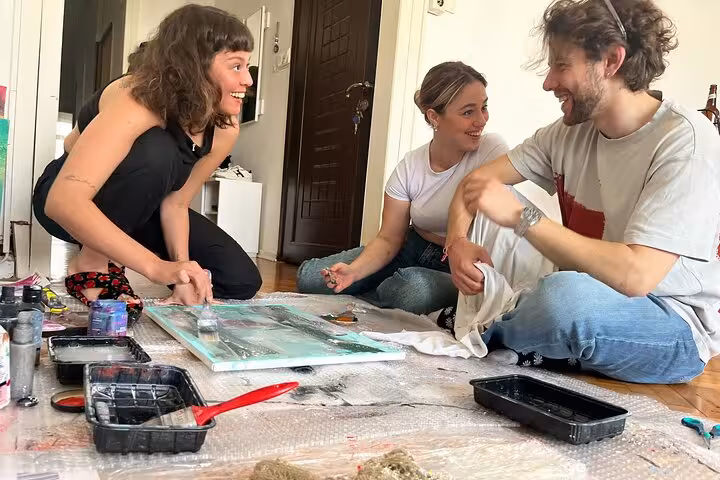 Friends laugh during Istanbul art escape wine and paint workshop at a local’s home, creating canvases
