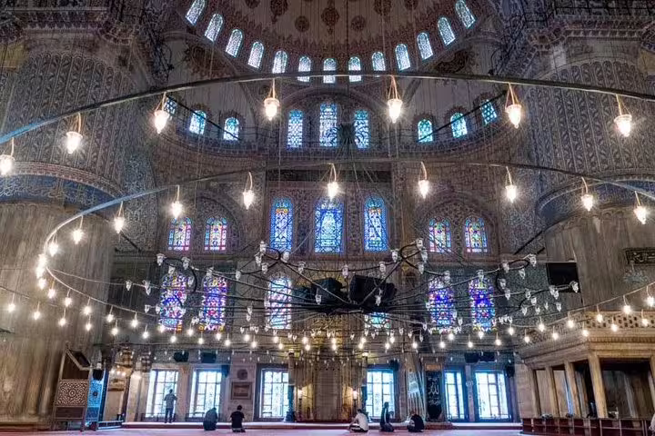 Interior view of the Blue Mosque with its grand stained glass windows and chandeliers on Istanbul private tour.