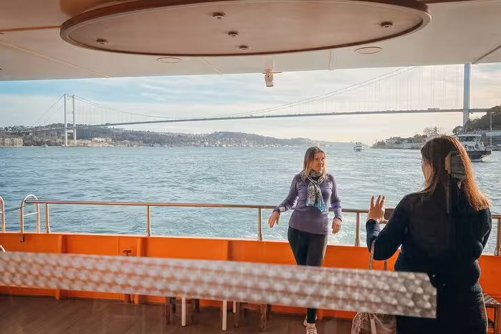 Guests enjoying Bosphorus sightseeing on Istanbul dinner cruise deck with bridge views and daytime sea breeze