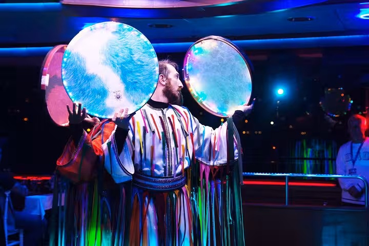Turkish night show on Bosphorus dinner cruise in Istanbul with drummer playing large frame drums under neon lights