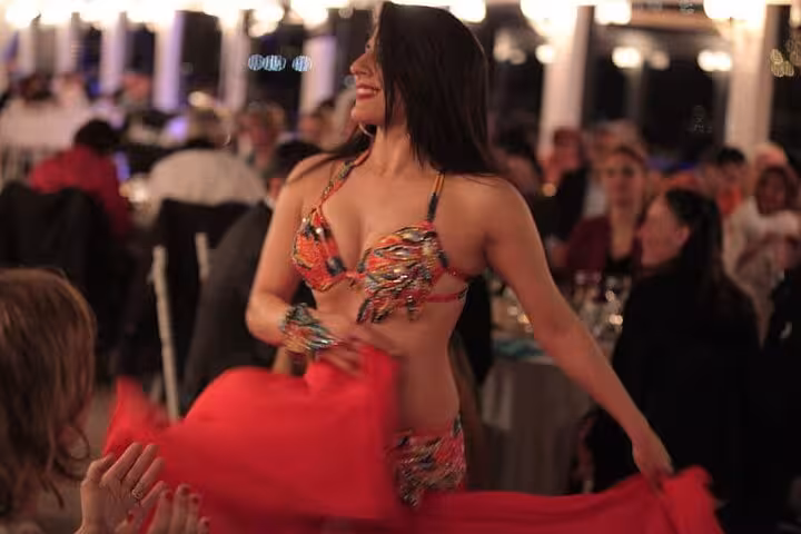 Belly dancer performing live on Istanbul Bosphorus New Year’s Eve dinner cruise party with festive crowd
