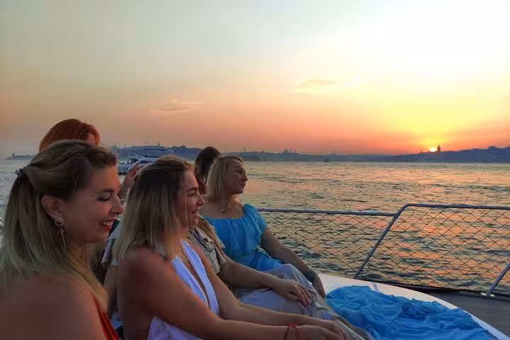 Guests relax on a luxury yacht during an Istanbul Bosphorus sunset cruise, sipping wine over golden waters