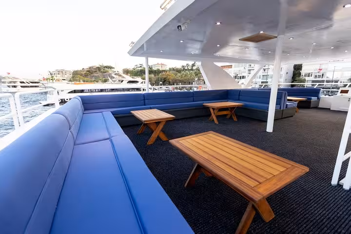 Spacious yacht lounge deck with blue seating and teak tables for a private Istanbul Bosphorus cruise