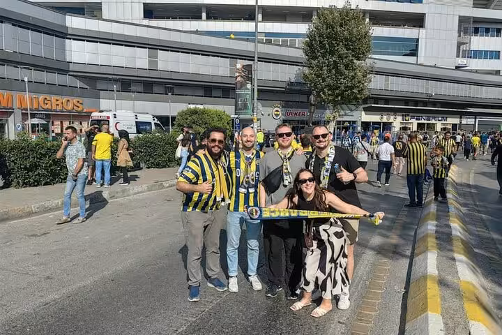 Travelers in Fenerbahçe colors posing outside Istanbul stadium before joining a local pickup football game tour