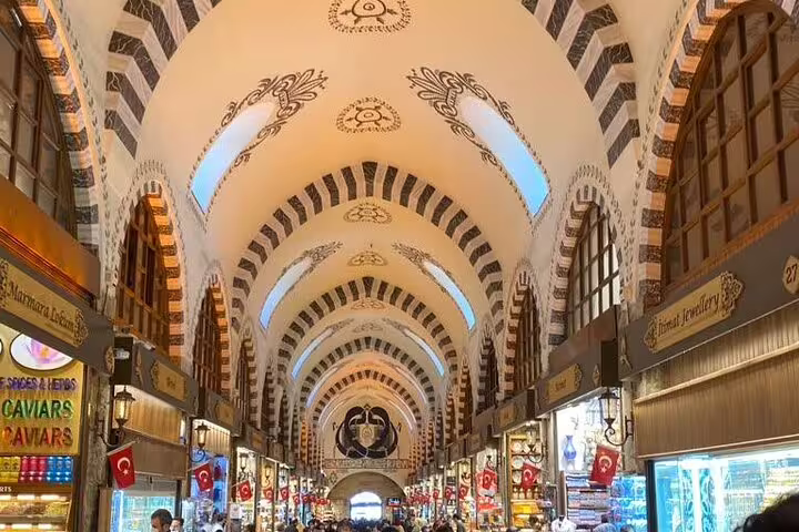 Grand Bazaar vaulted corridor with shops and Turkish flags, Istanbul private mini group shore excursion from port