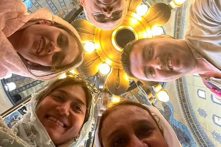 Happy group of tourists under ornate chandelier in a historic Istanbul mosque on the SKIP-THE-LINE private tour from Galataport.