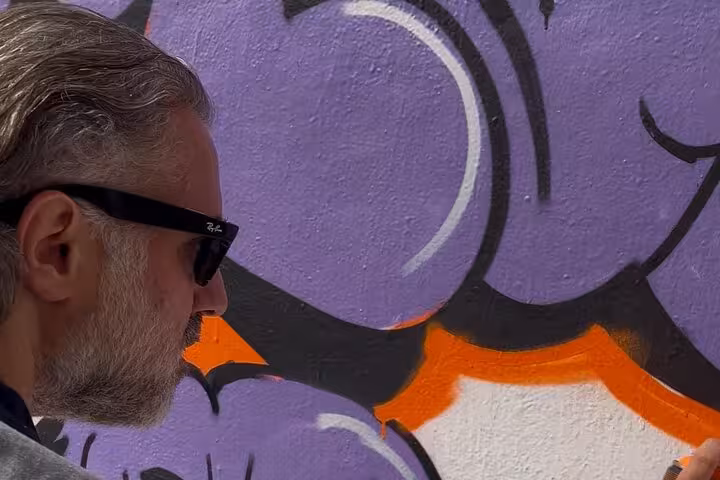 Local artist painting bold graffiti details during Istanbul street art workshop in a home garden setting