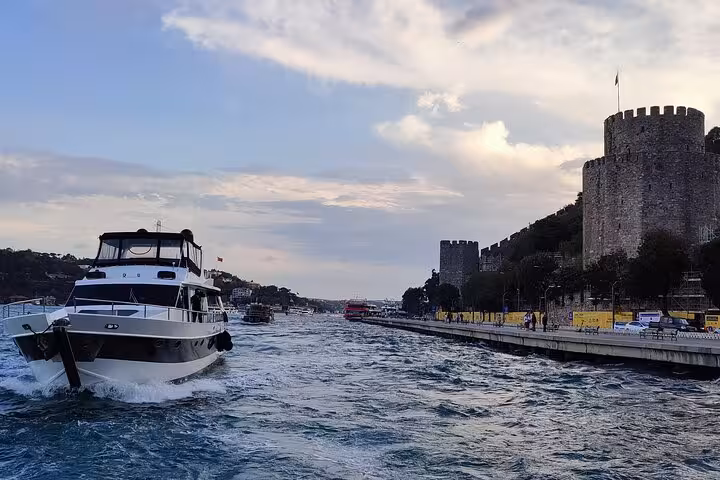 Luxury yacht cruising the Bosphorus at sunset near Rumeli Fortress on an Istanbul evening cruise tour
