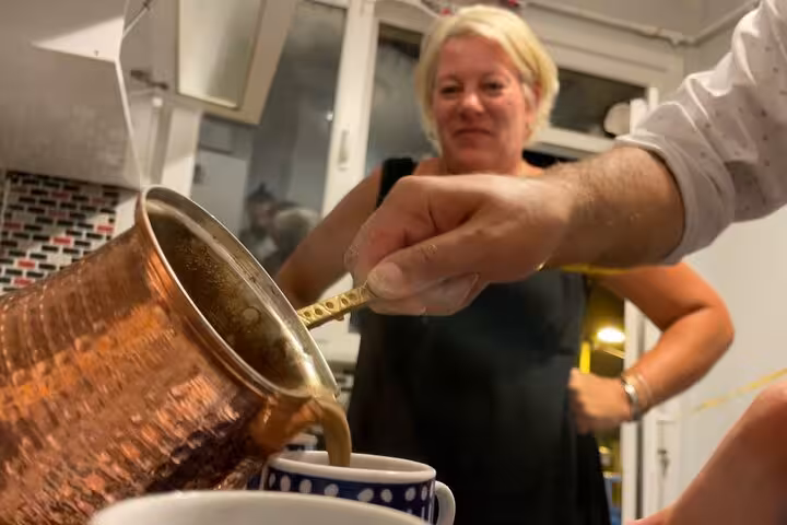 Pouring foamy Turkish coffee from a copper cezve into a cup during an Istanbul home cooking and tasting
