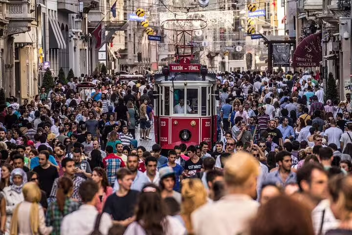 Crowded Istiklal Avenue in Istanbul with iconic red tram, highlighting vibrant city life on guided tours.