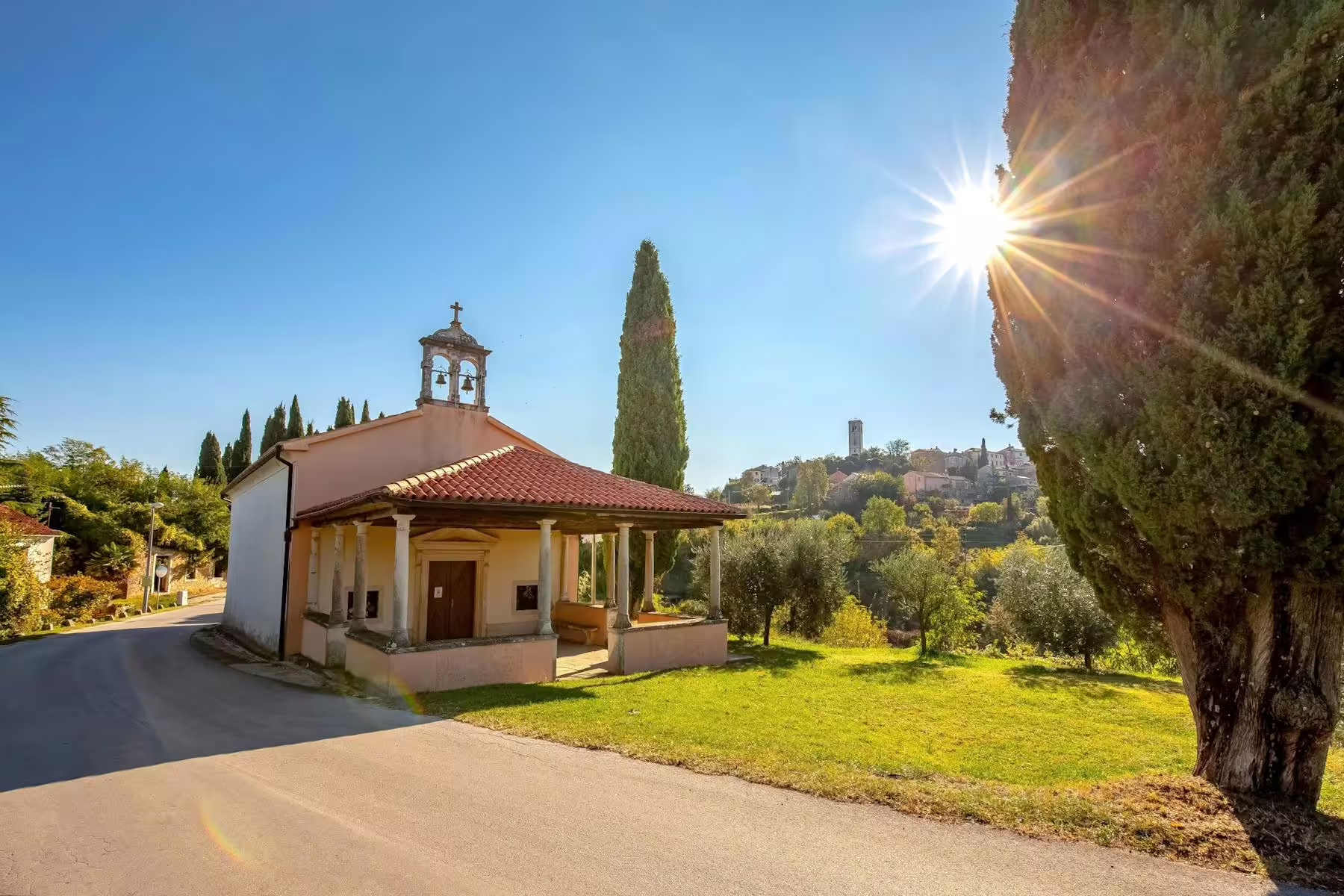 Sunny chapel beside olive groves with hilltop village views in Istria, Croatia, on a local tasting tour