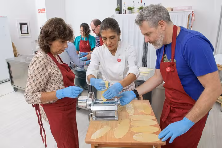 Hands-on pasta making class with an Italian chef guiding students in rolling fresh dough in a culinary workshop.