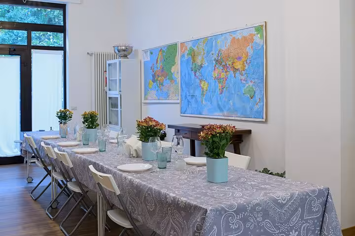 Elegant dining area with long table setup for Italian cooking class, featuring world maps and vibrant potted plants.