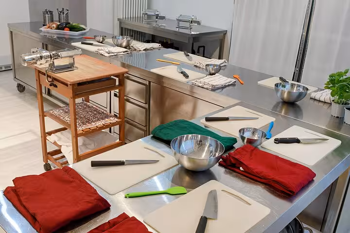 Modern Italian cooking class setup with pasta machines and vibrant cloths in a professional kitchen.