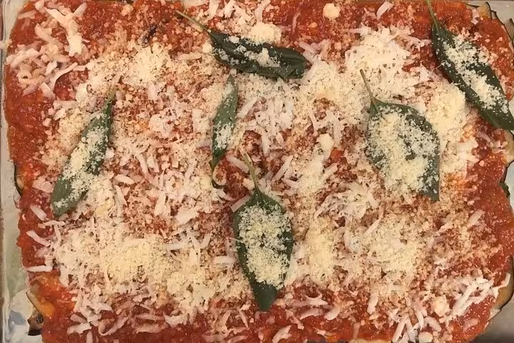 Delicious homemade lasagna topped with tomato sauce, parmesan cheese, and fresh basil leaves in an Italian cooking class.