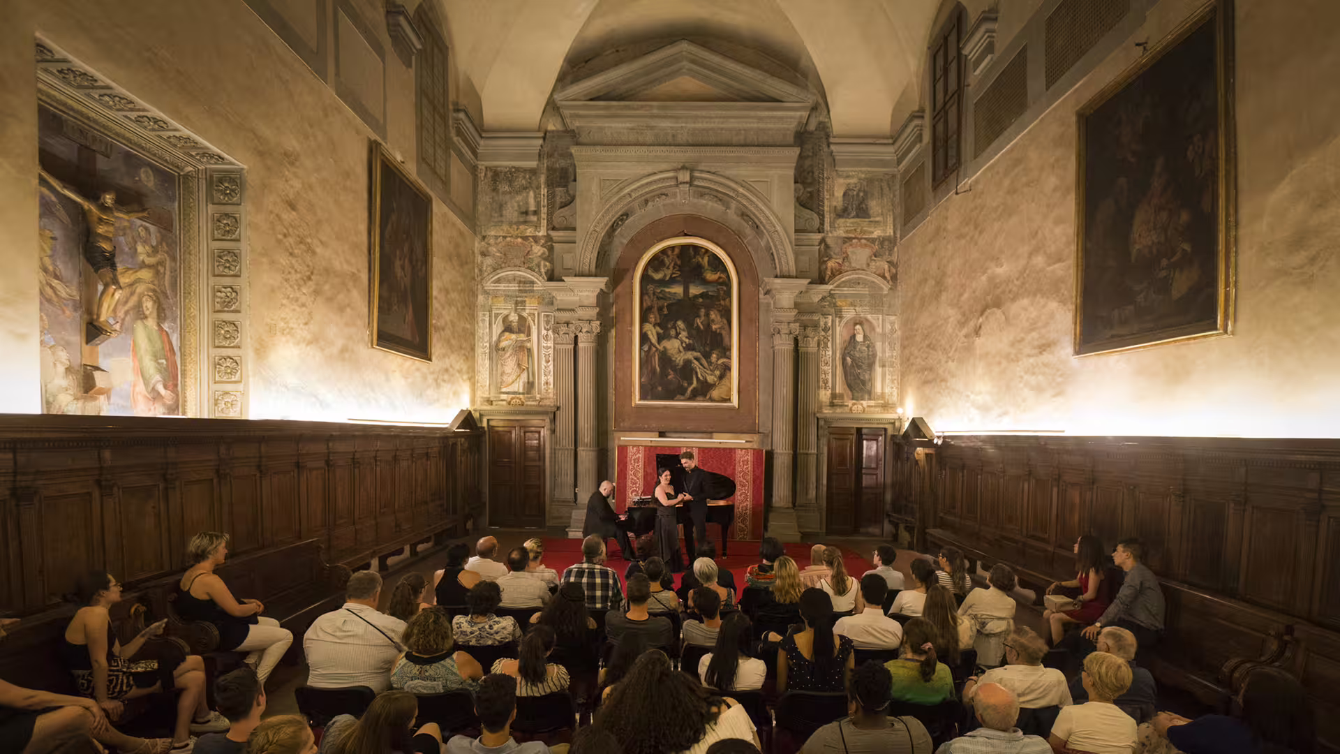 Audience enjoying Italian opera concert at Santa Monaca Church in Florence with live soprano and piano