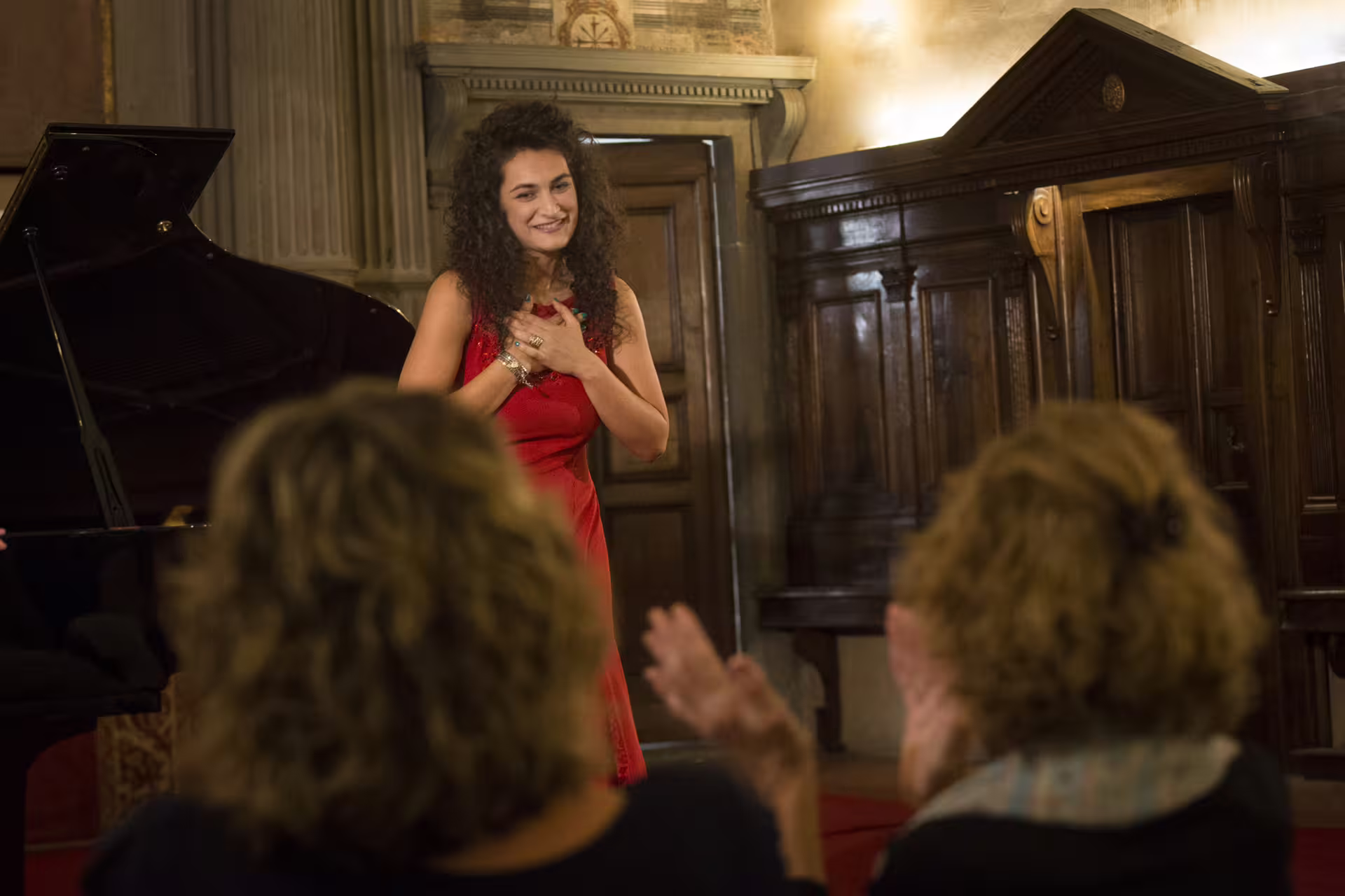 Opera vocalist in red thanks the audience after a Santa Monaca Church Italian opera concert in Rome with piano