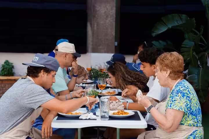Group of people savoring Italian dishes at a communal dining table during the pasta-making class in Barcelona.