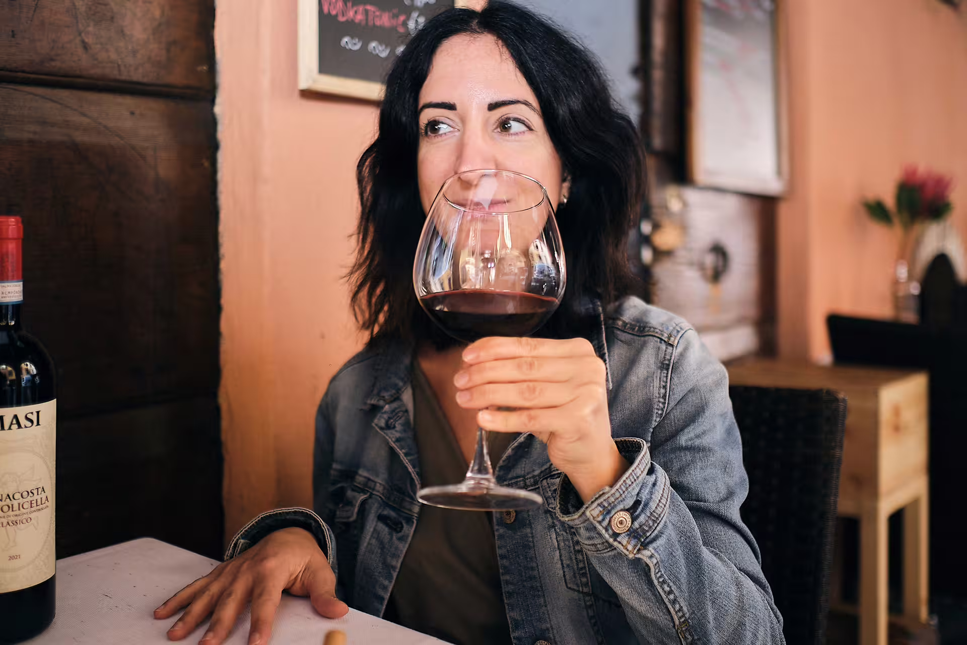 Guest savoring Italian red wine at a cozy Genoa wine tasting near the Aquarium, guided local experience.