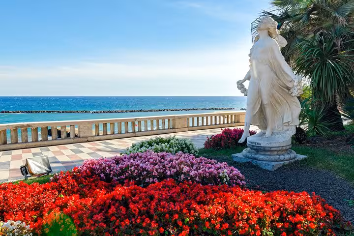 Primavera marble statue surrounded by colorful flowers on Italian Riviera promenade overlooking the sea