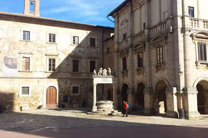 Historic stone piazza with fountain and arches in Tuscany, cultural stop on Rome Florence Pisa Milan Venice tour