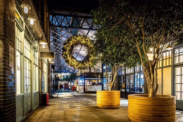 Atmospheric Victorian market hall at night with glowing Christmas wreath and trees in London